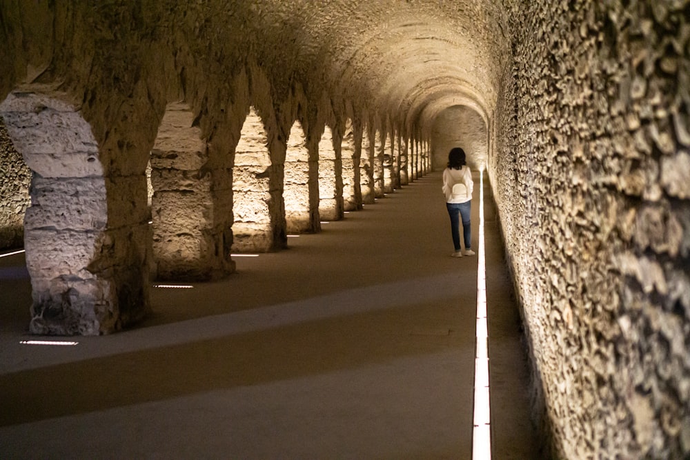 a woman walking down a tunnel of stone
