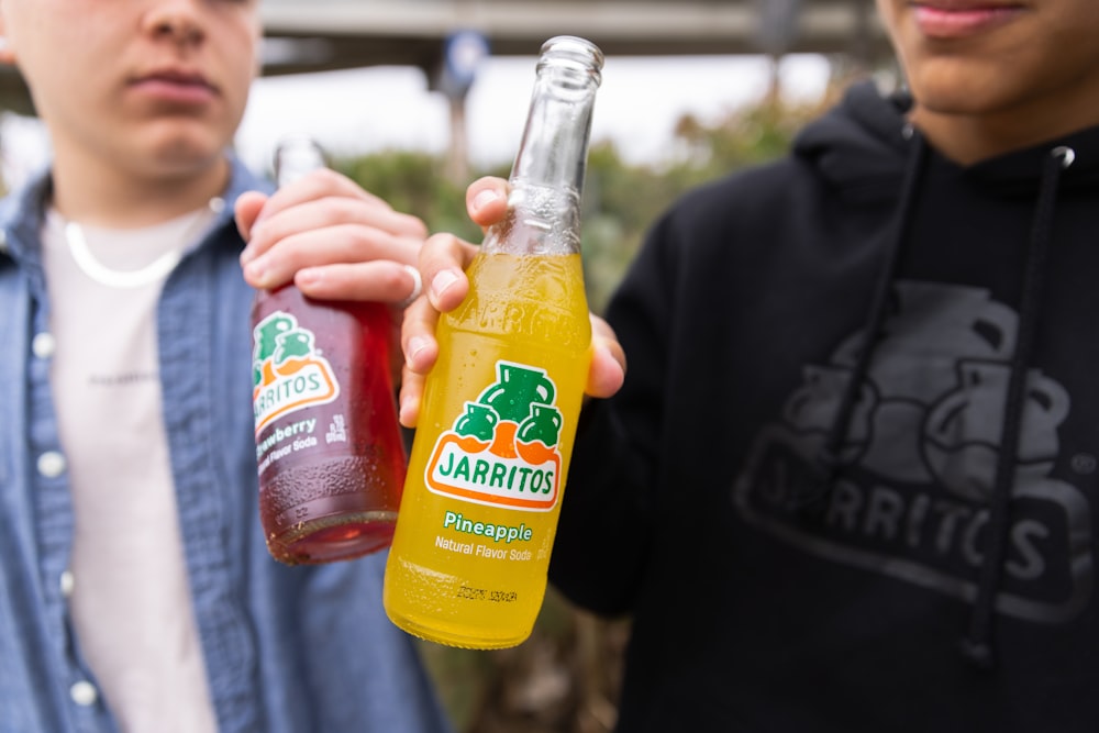 a man holding a bottle of orange juice next to another man