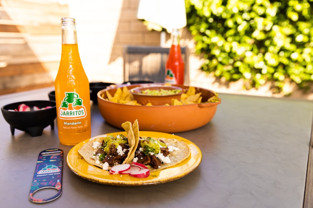 a table topped with a plate of food and a bottle of orange juice