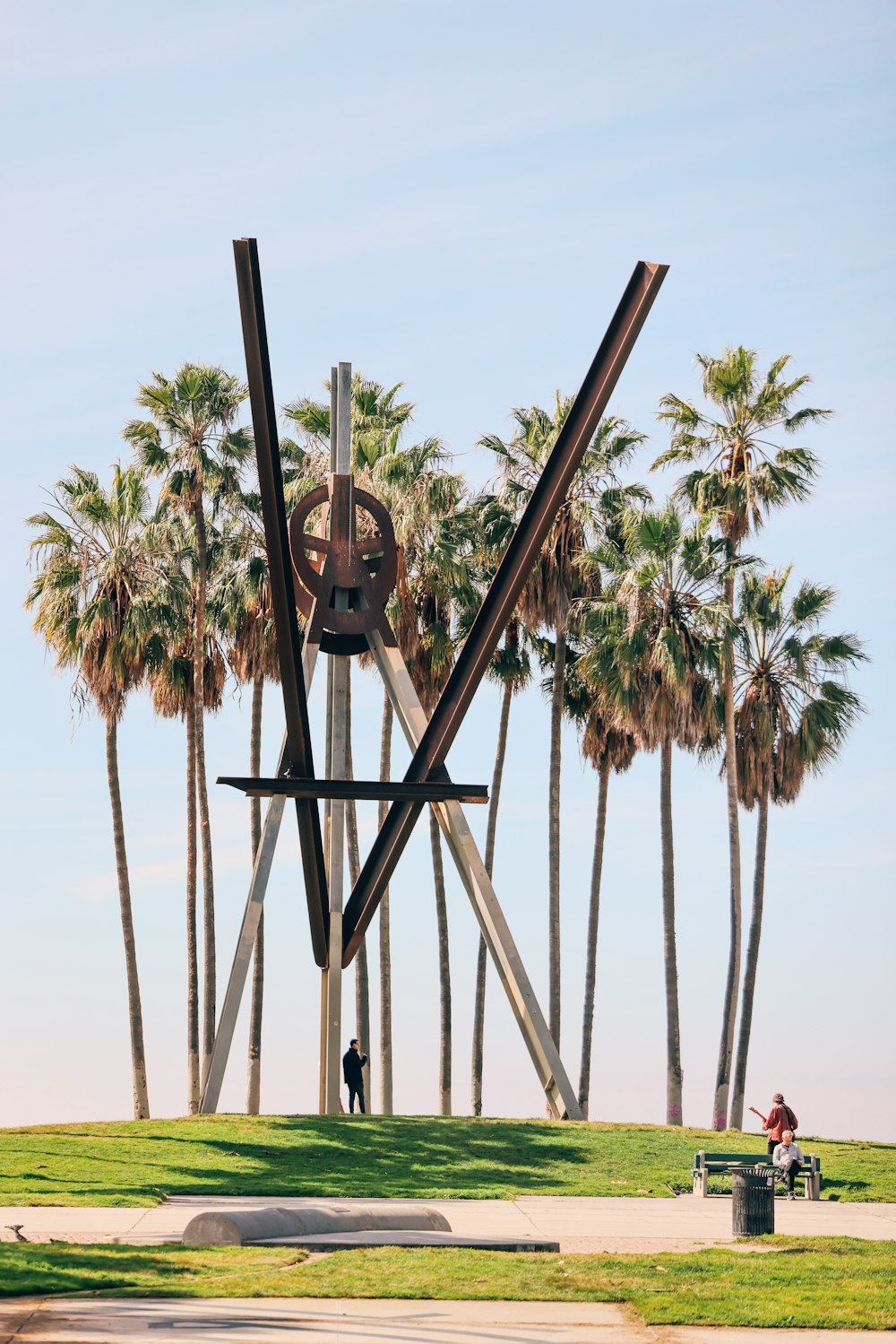 a sculpture in a park with palm trees in the background