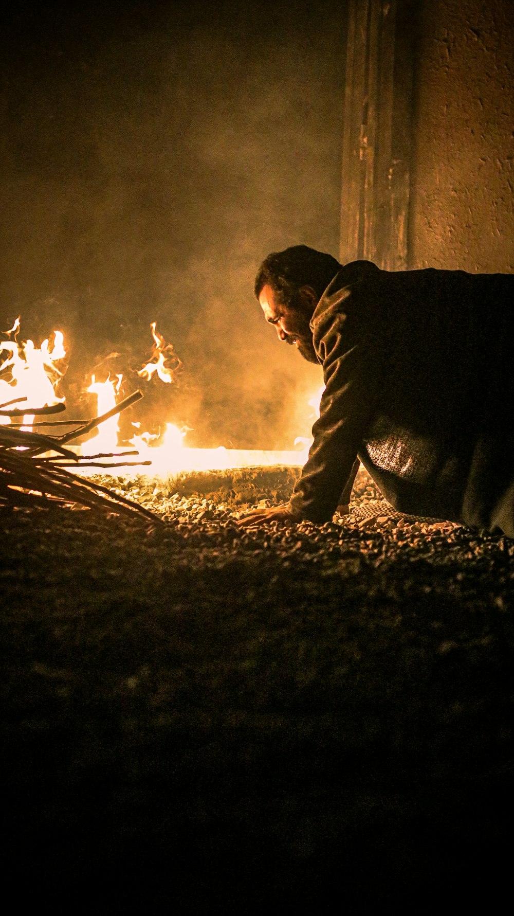 a man kneeling down in front of a fire