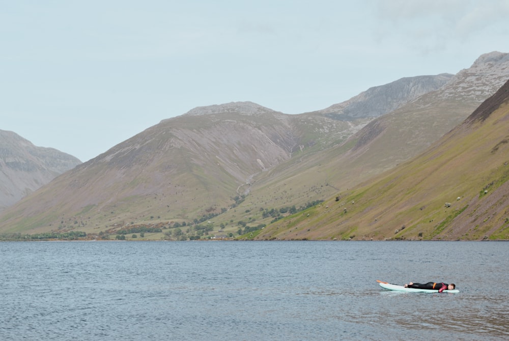 a person in a boat on a lake with mountains in the background