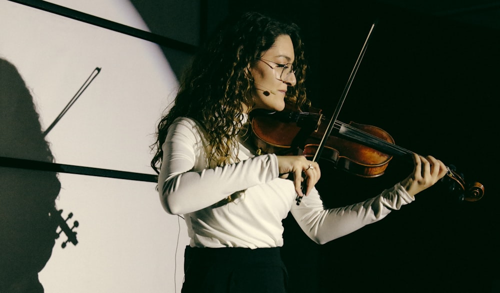 a woman in a white shirt playing a violin