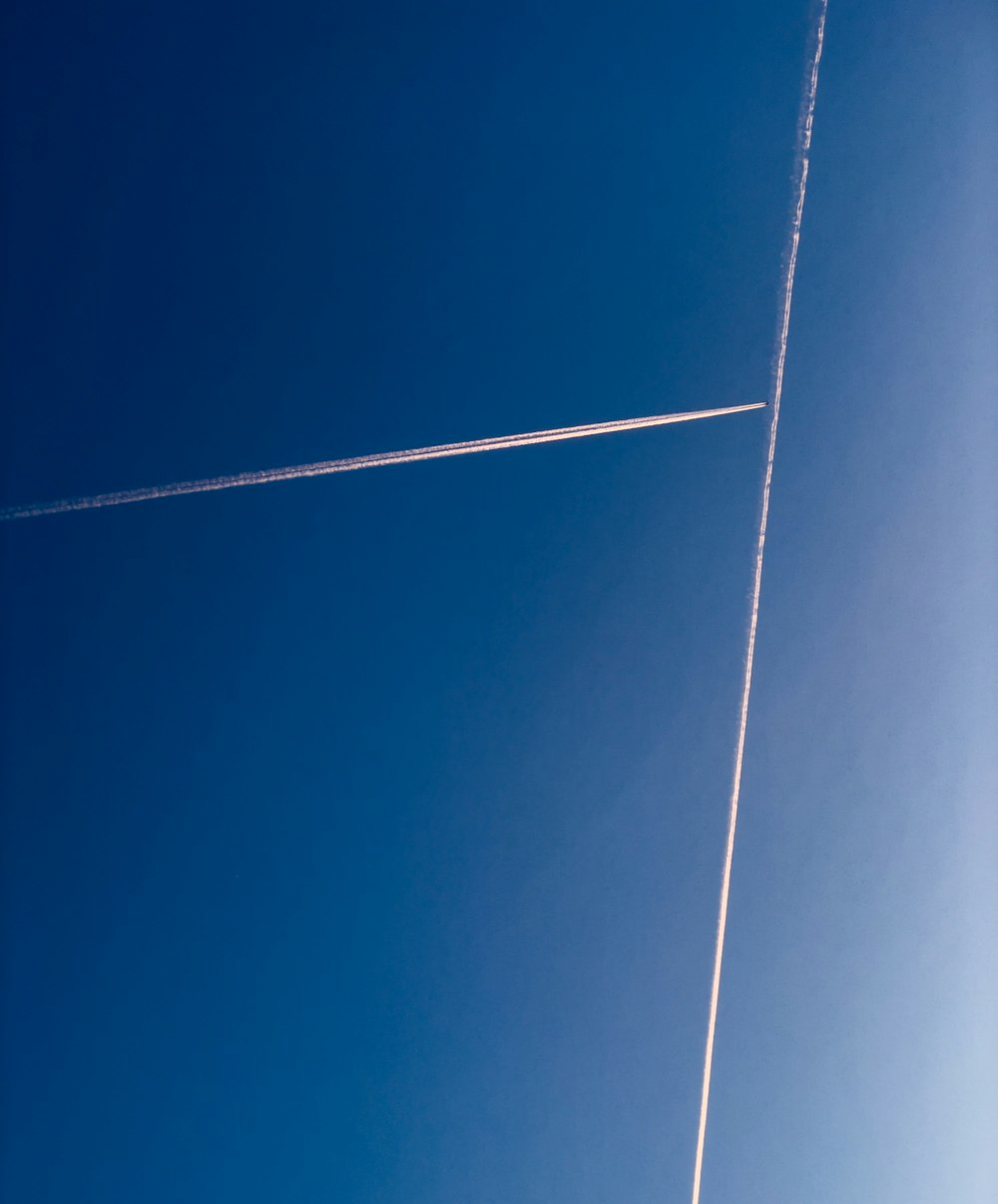 a jet flying through a blue sky with a contrail in the sky