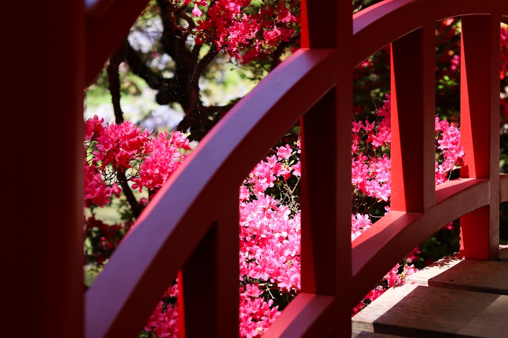 a close up of a red wooden fence with flowers in the background