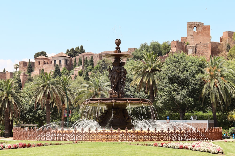 a fountain surrounded by palm trees in a park