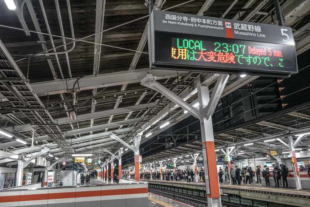 uma estação de trem com pessoas em pé na plataforma