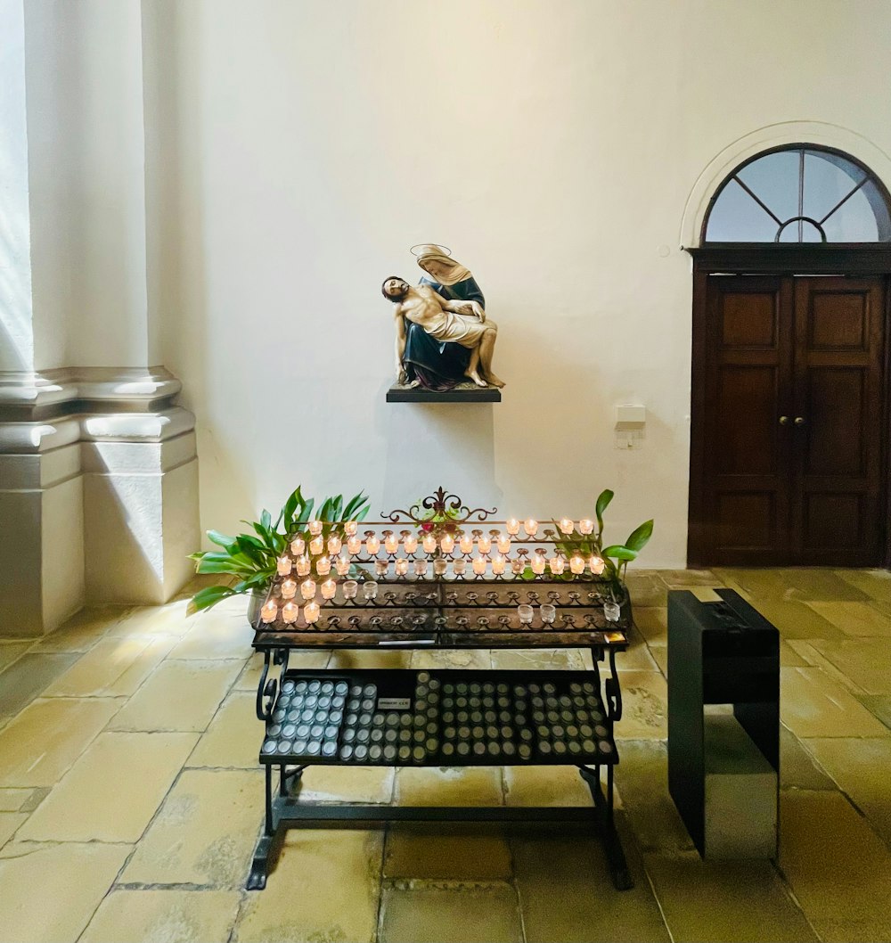 a table with candles and a statue in the background
