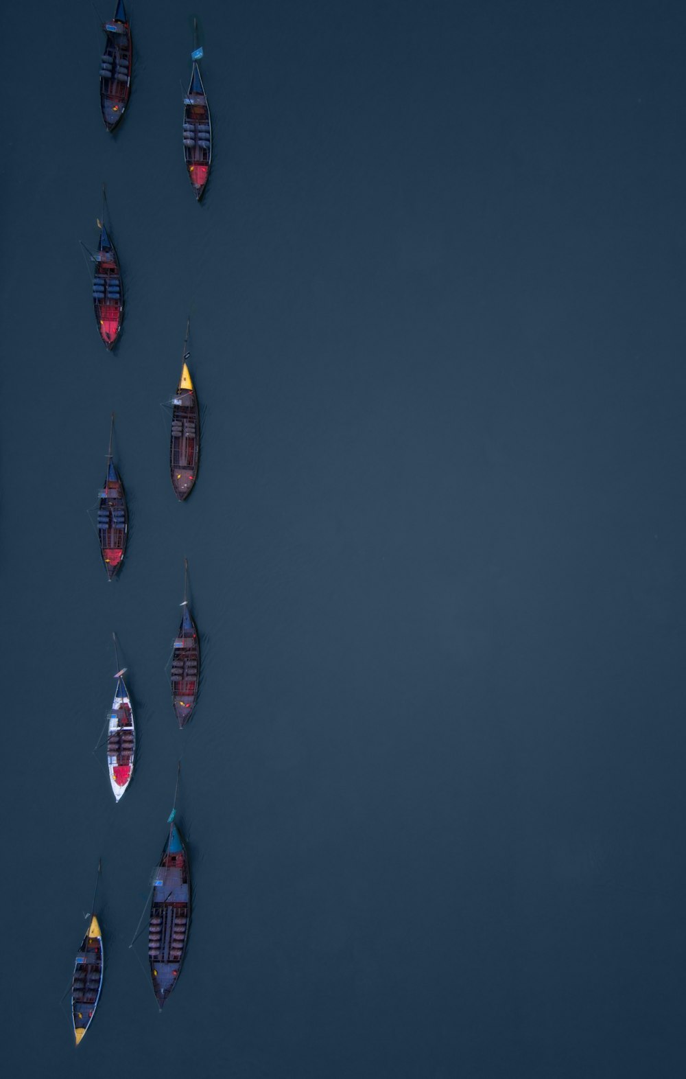 un gruppo di piccole barche che galleggiano sulla cima di uno specchio d'acqua