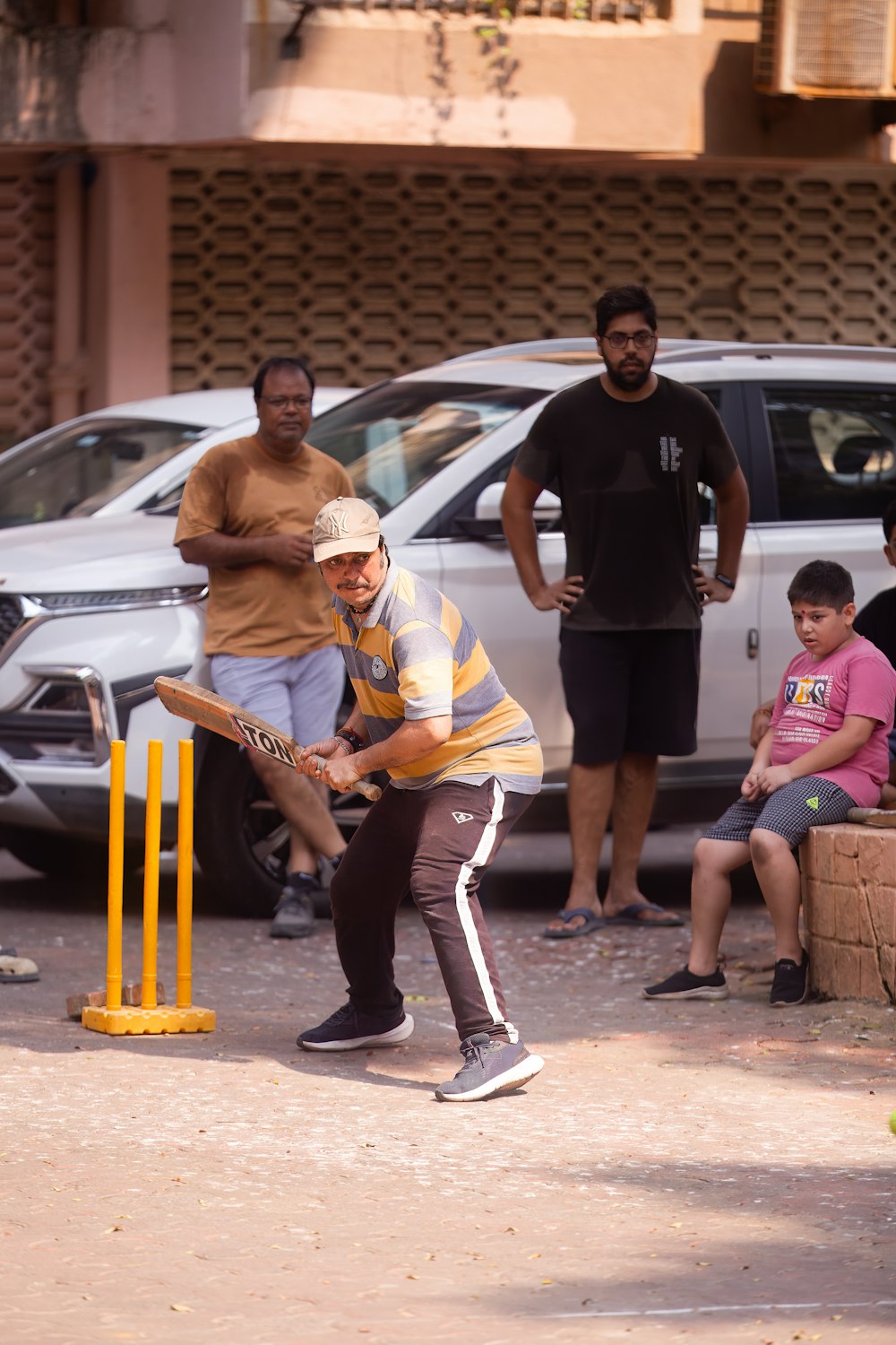 a man playing a game of cricket with a group of people watching