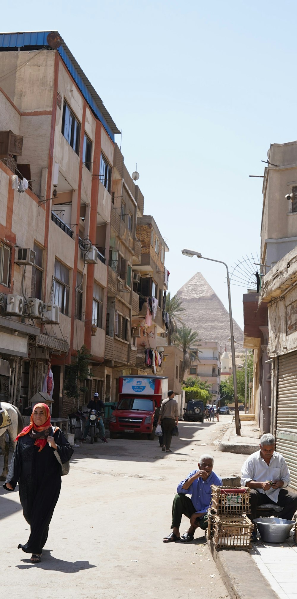 a woman walking down a street next to tall buildings