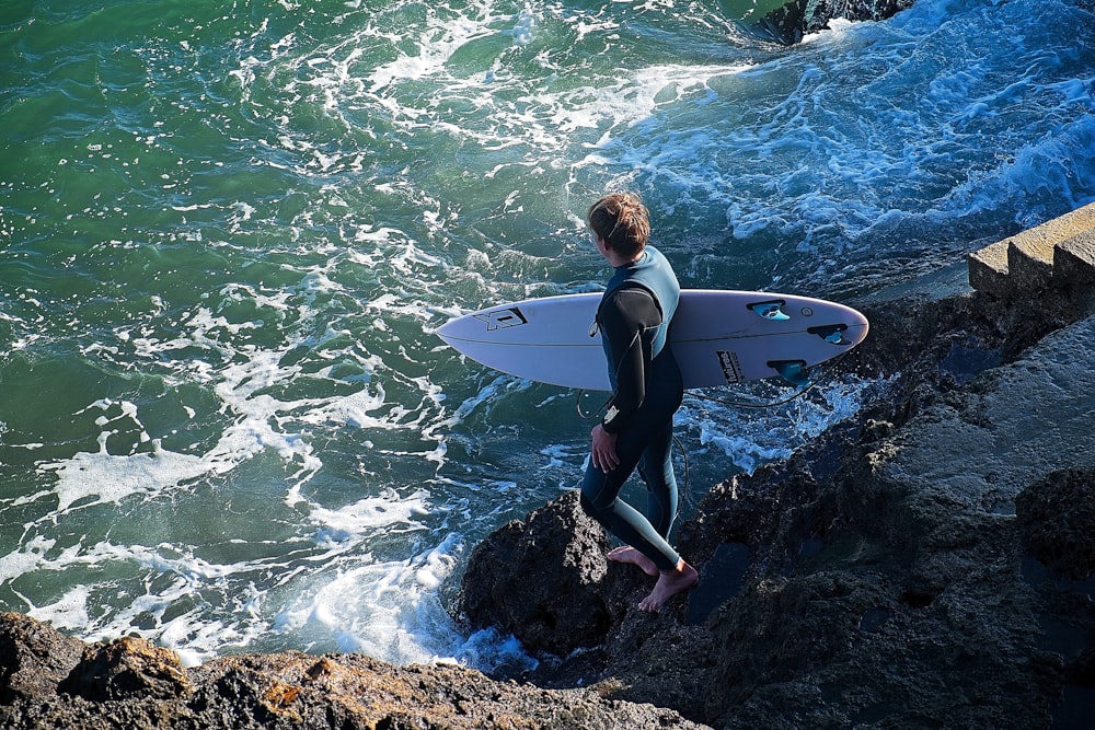 a man in a wet suit carrying a surfboard into the ocean