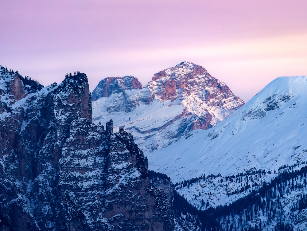 a snow covered mountain range with a pink sky