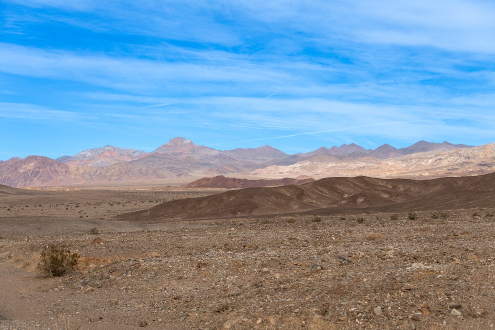 a dirt field with mountains in the background