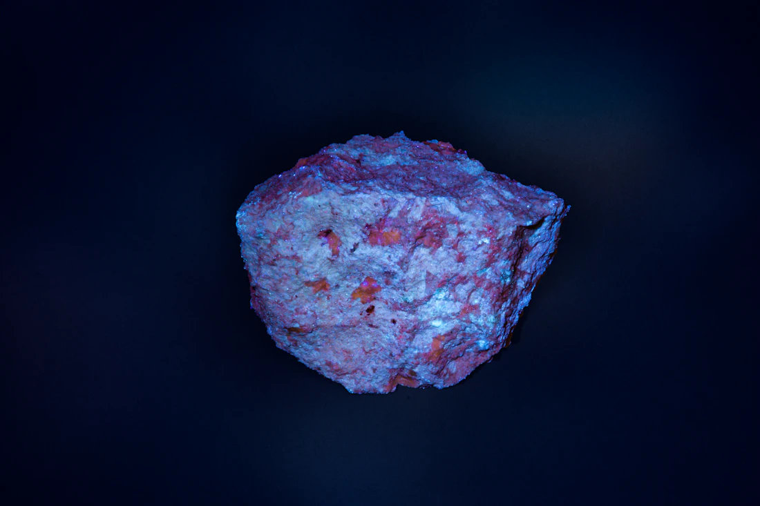 Genuine photograph of a lithium-bearing pegmatite specimen photographed under ultraviolet light in Portugal