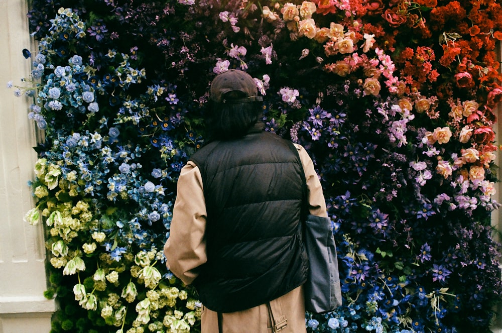 a person standing in front of a wall of flowers
