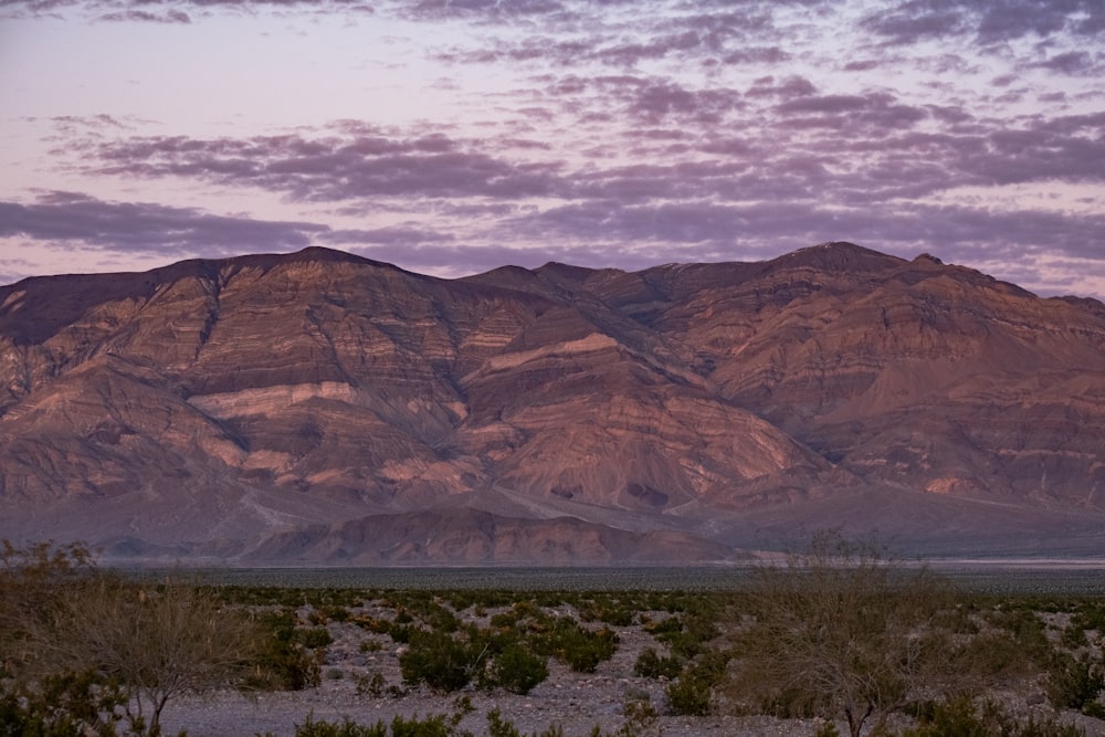 a large mountain range in the distance with a purple sky