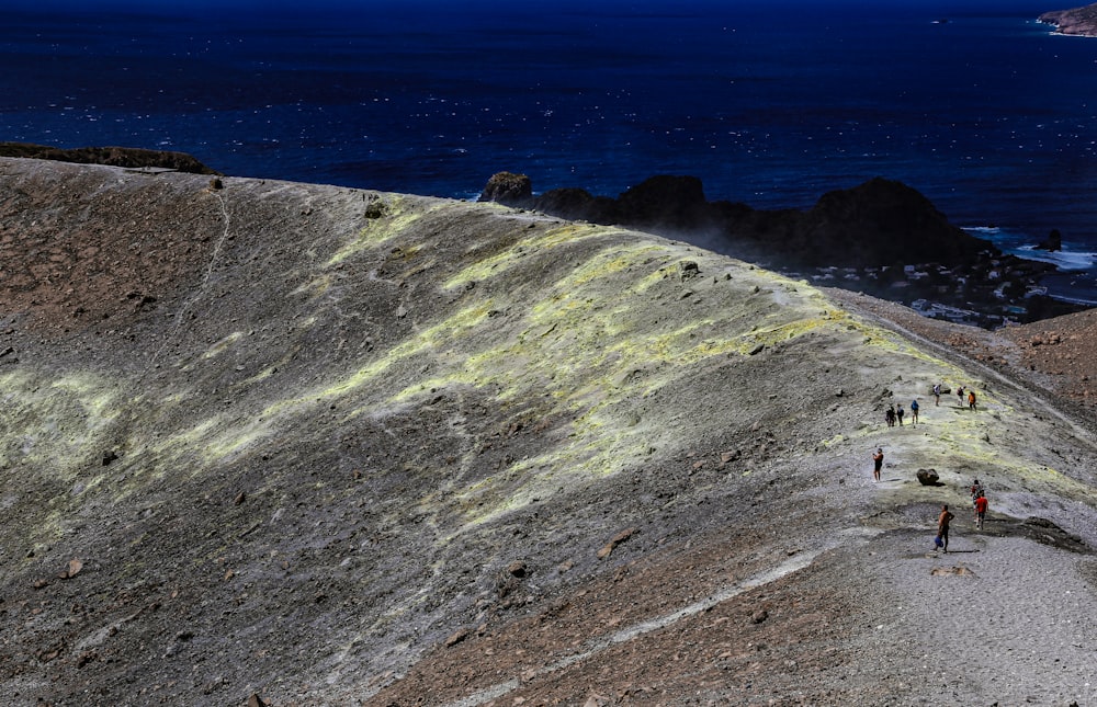 un groupe de personnes marchant sur une colline à côté de l’océan