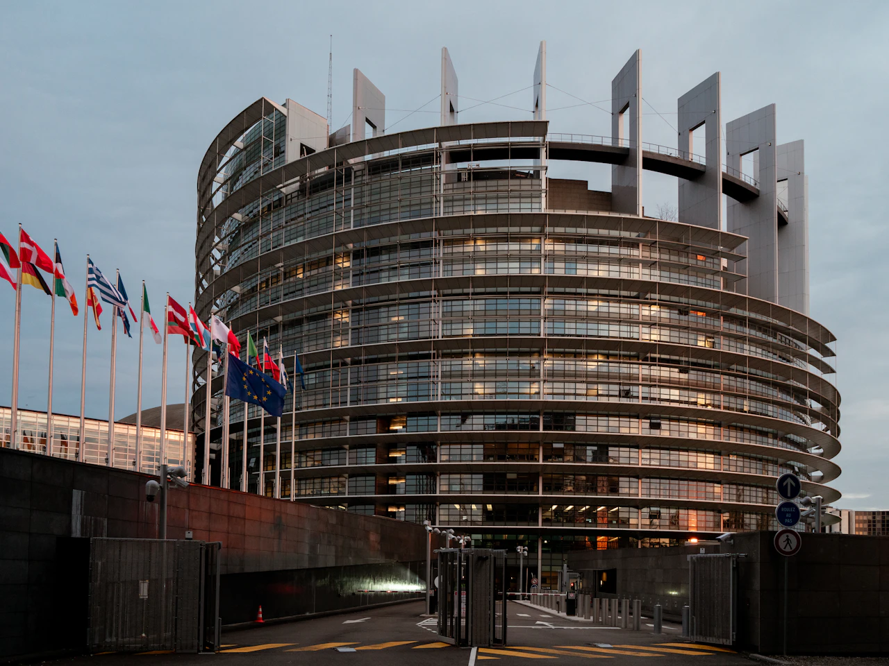 European Parliament building with member state flags at dusk