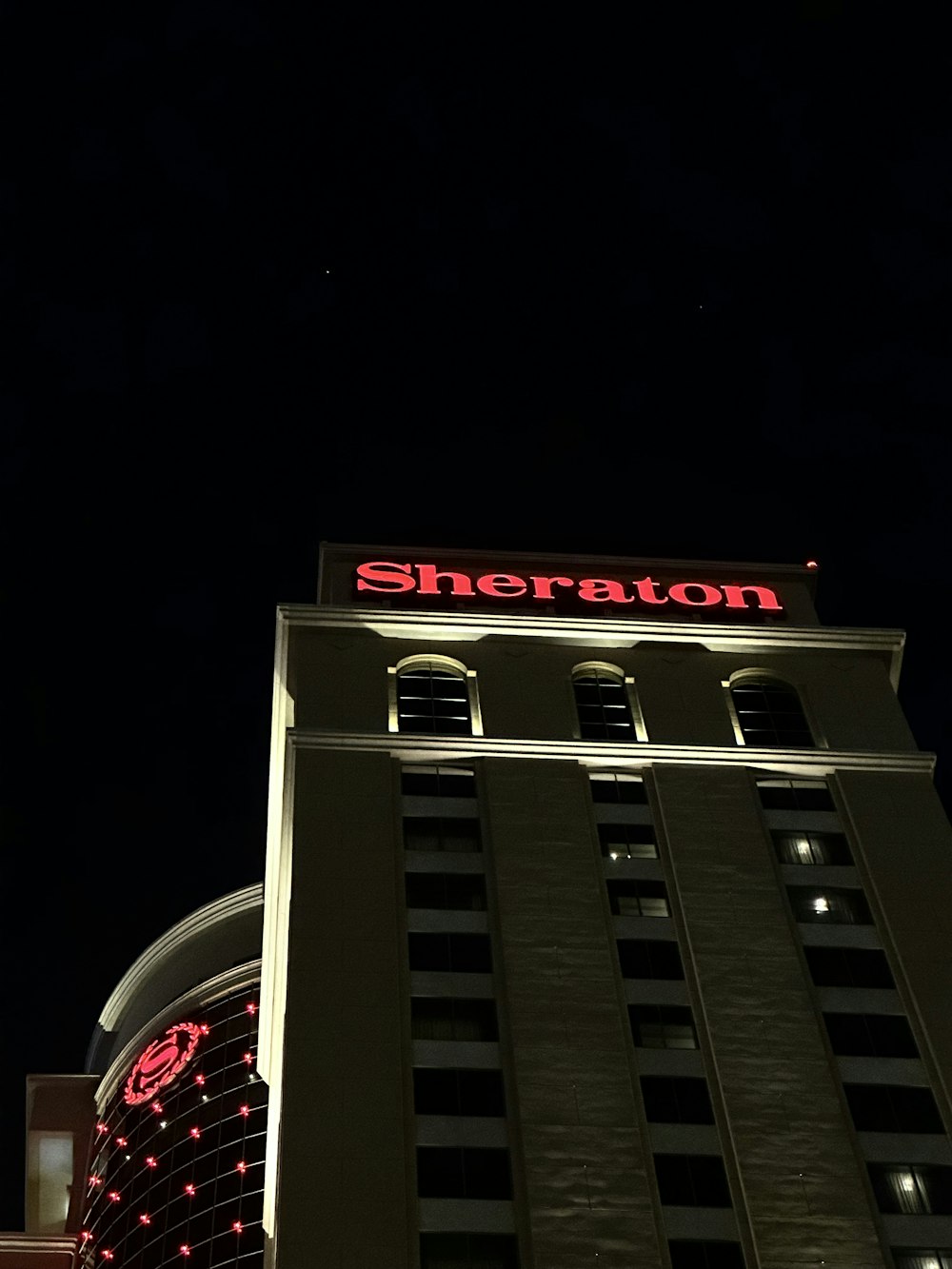 Un edificio alto y blanco con un letrero rojo en la parte superior