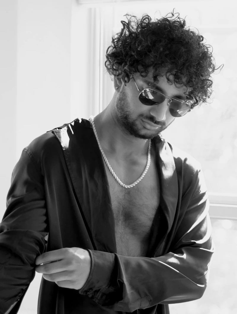 Adult man in a satin shirt wearing a heavy link chain, photographed in black and white