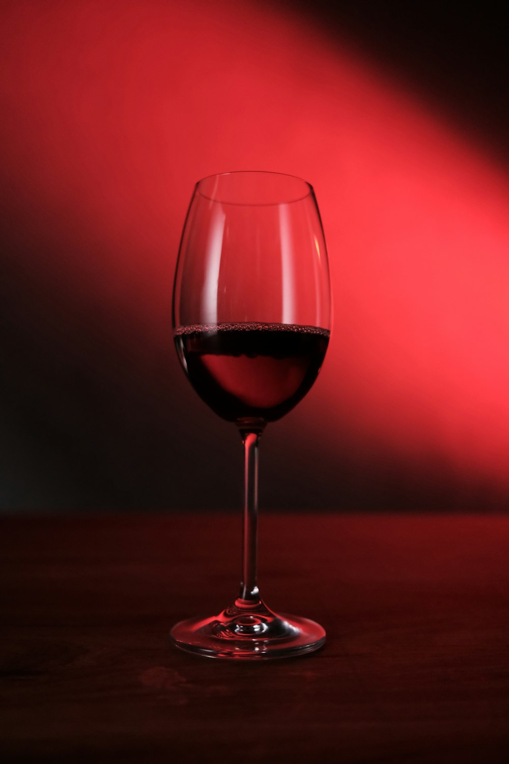 a glass of red wine sitting on a table