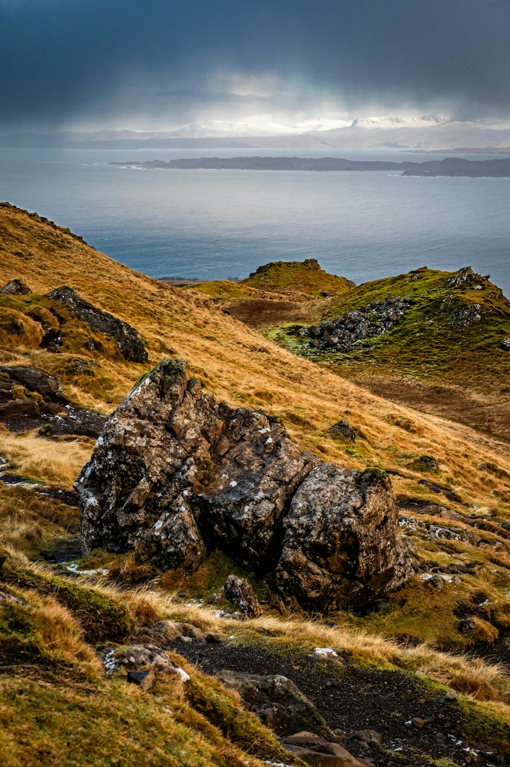 a large rock sitting on top of a grass covered hillside