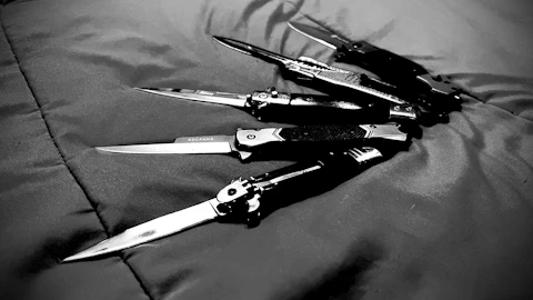 a group of knives laying on top of a bed