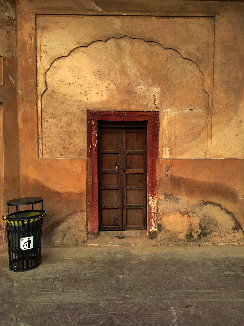 a door and a trash can in front of a wall