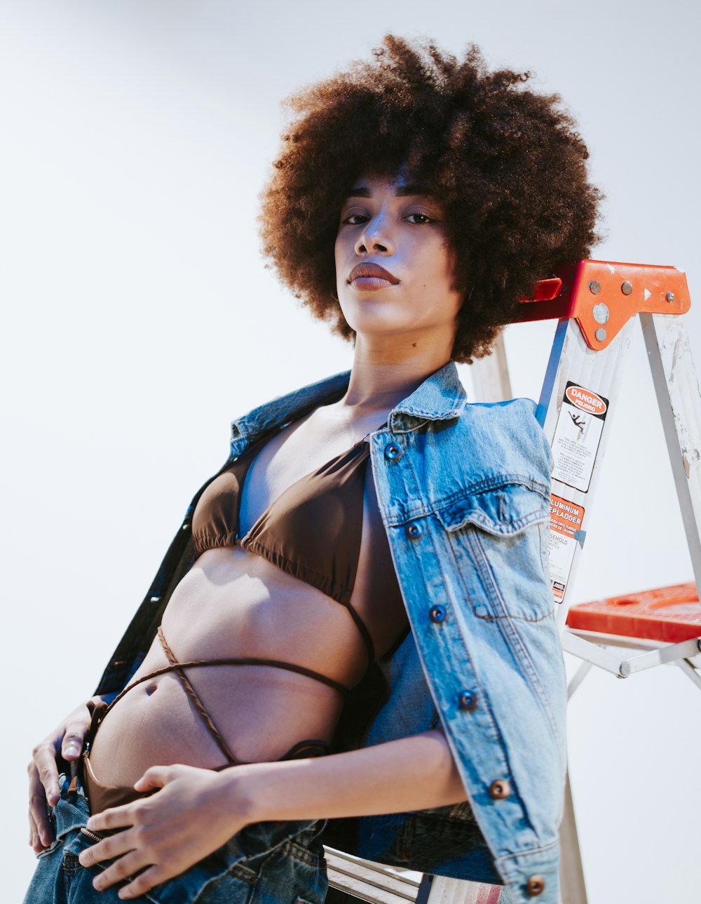 a woman with an afro standing next to a ladder