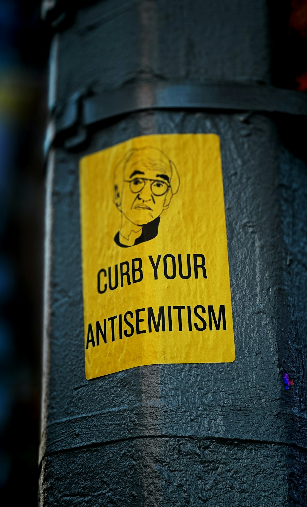 a sticker on the side of a pole that says curb your antisemit