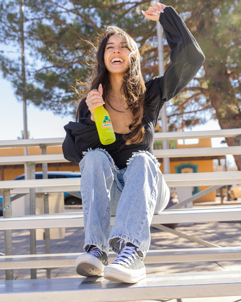 a woman sitting on a bench with her arms in the air