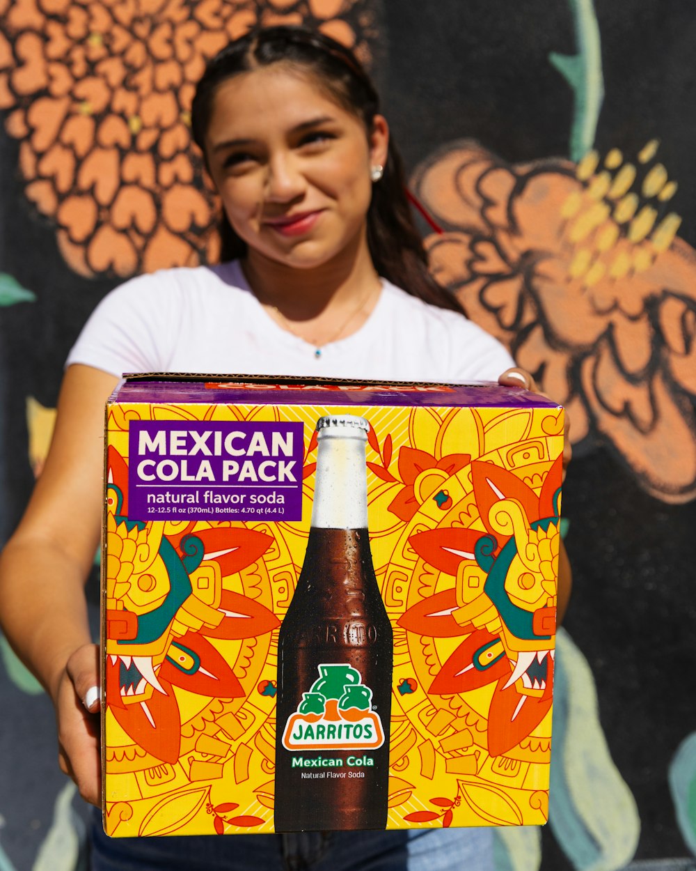 a woman holding a mexican beer in front of a mural