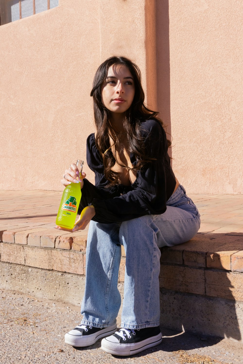 a woman sitting on a ledge with a bottle of water