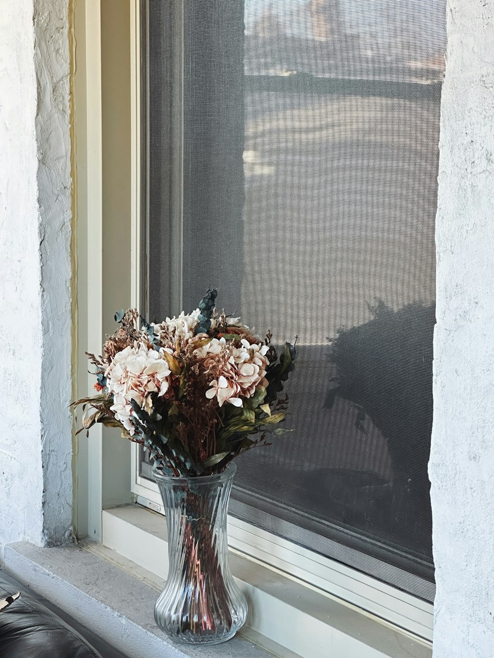 a vase of flowers sitting on a window sill