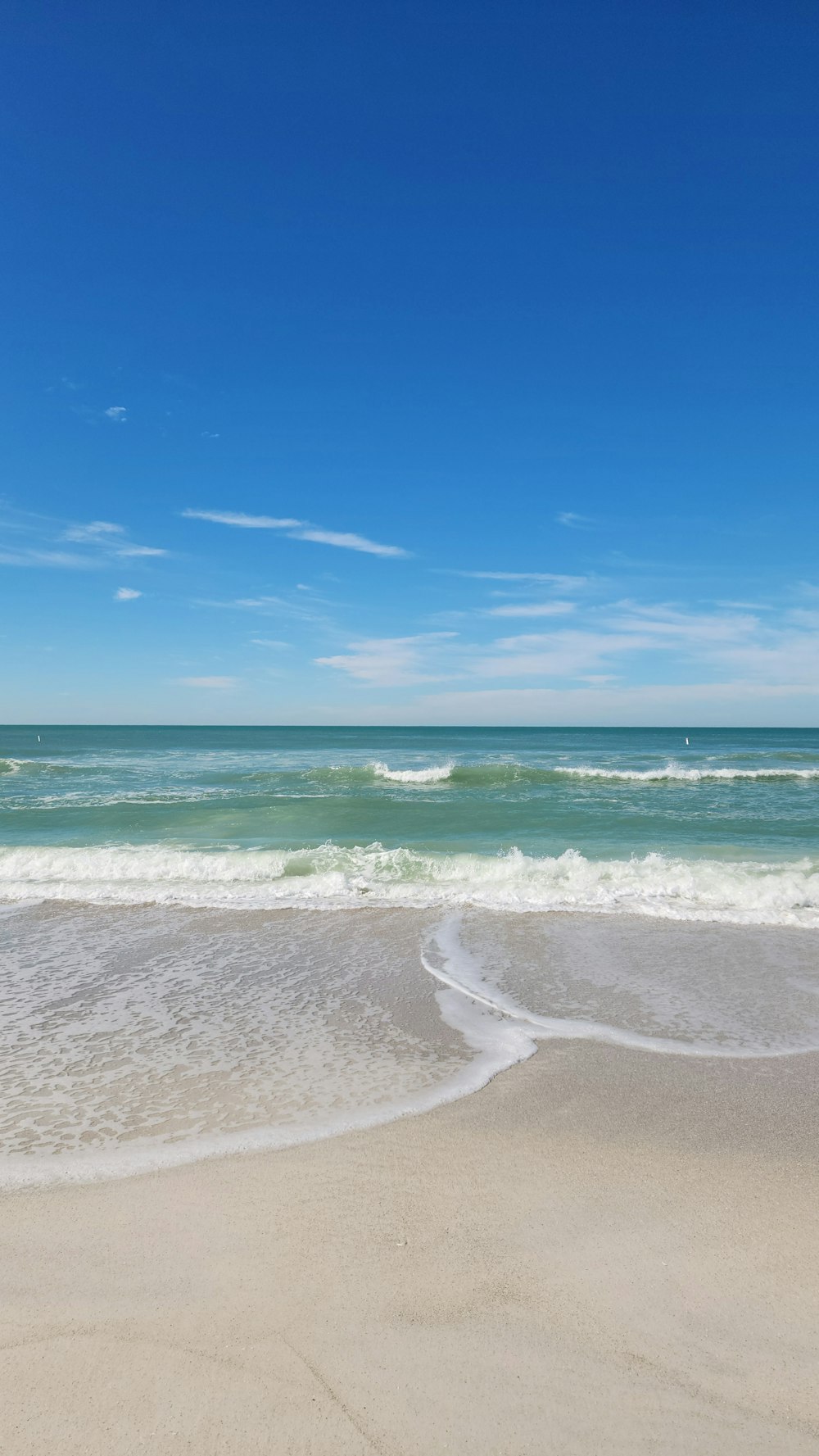 a sandy beach with waves coming in and out of the water