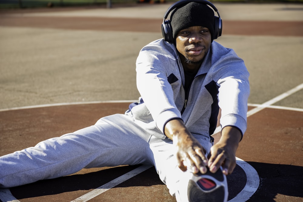 a man sitting on a tennis court wearing headphones