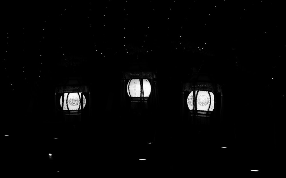 a black and white photo of three windows in a dark room