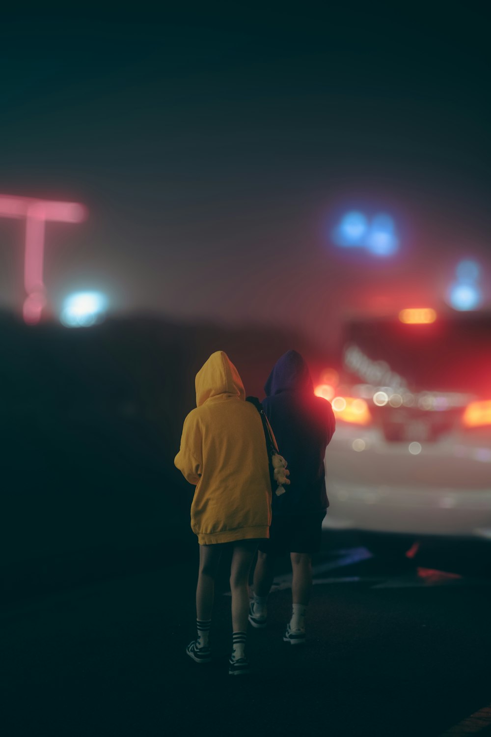two people standing on a road at night