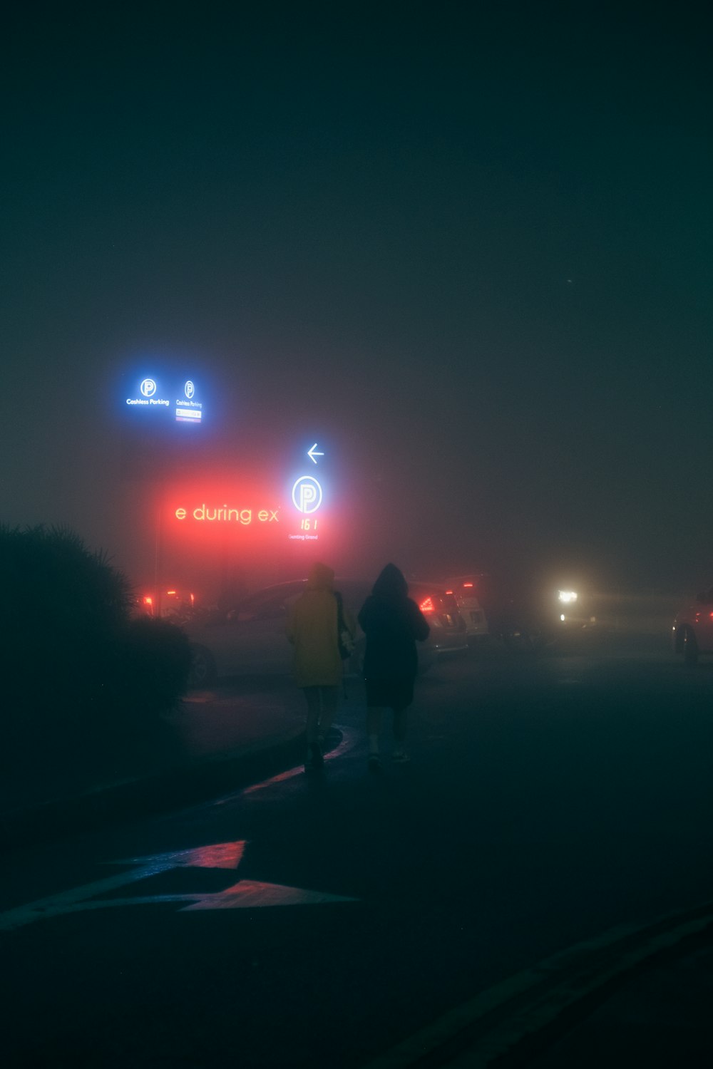 a couple of people walking down a street at night