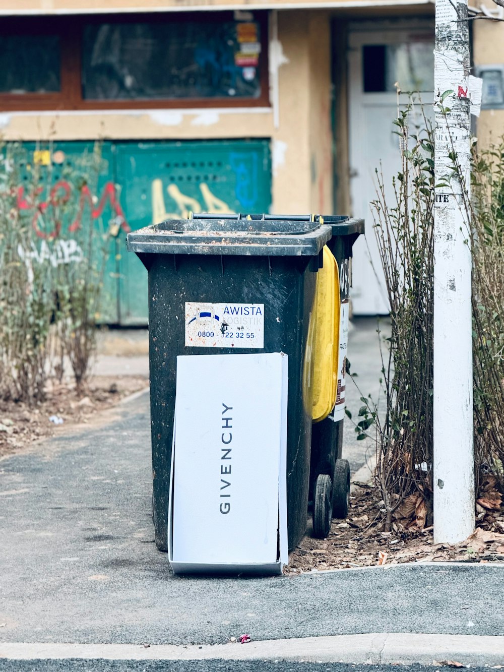 a trash can sitting on the side of a road