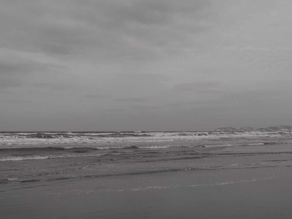 a black and white photo of a person walking on the beach