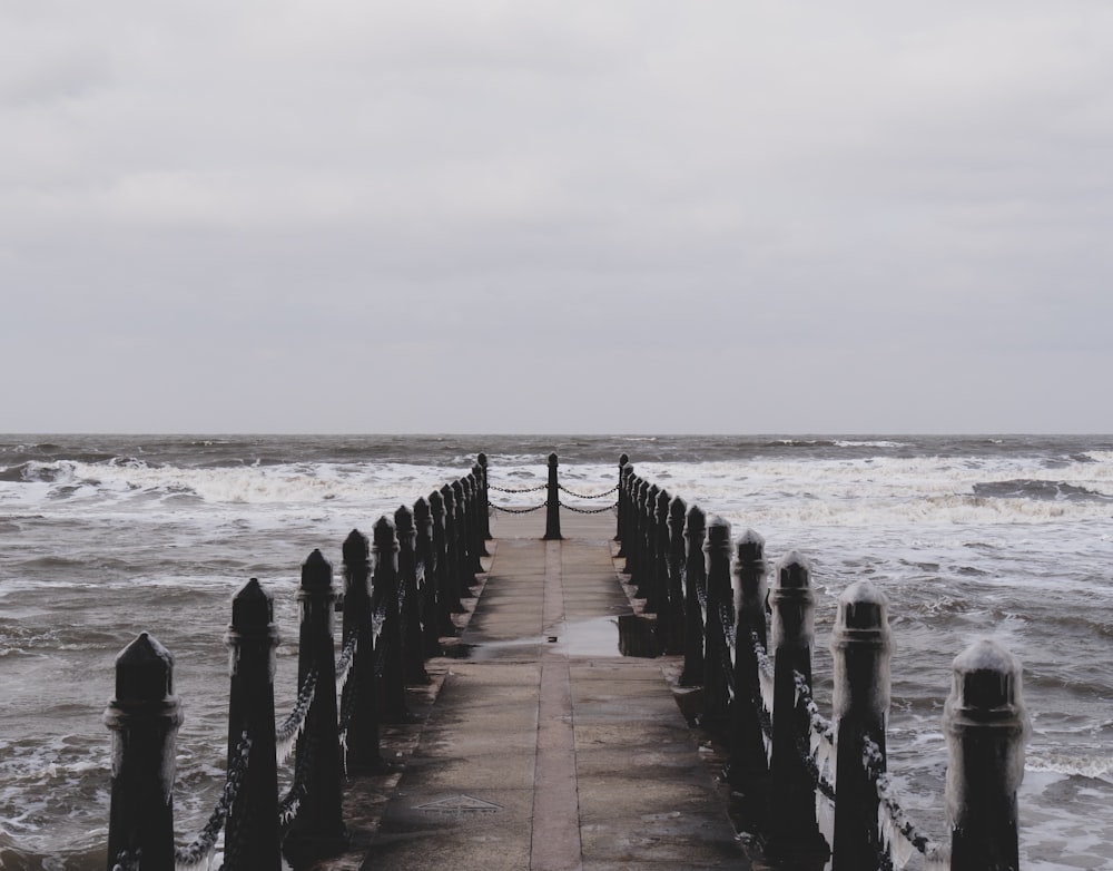 a long wooden pier with waves crashing in the background