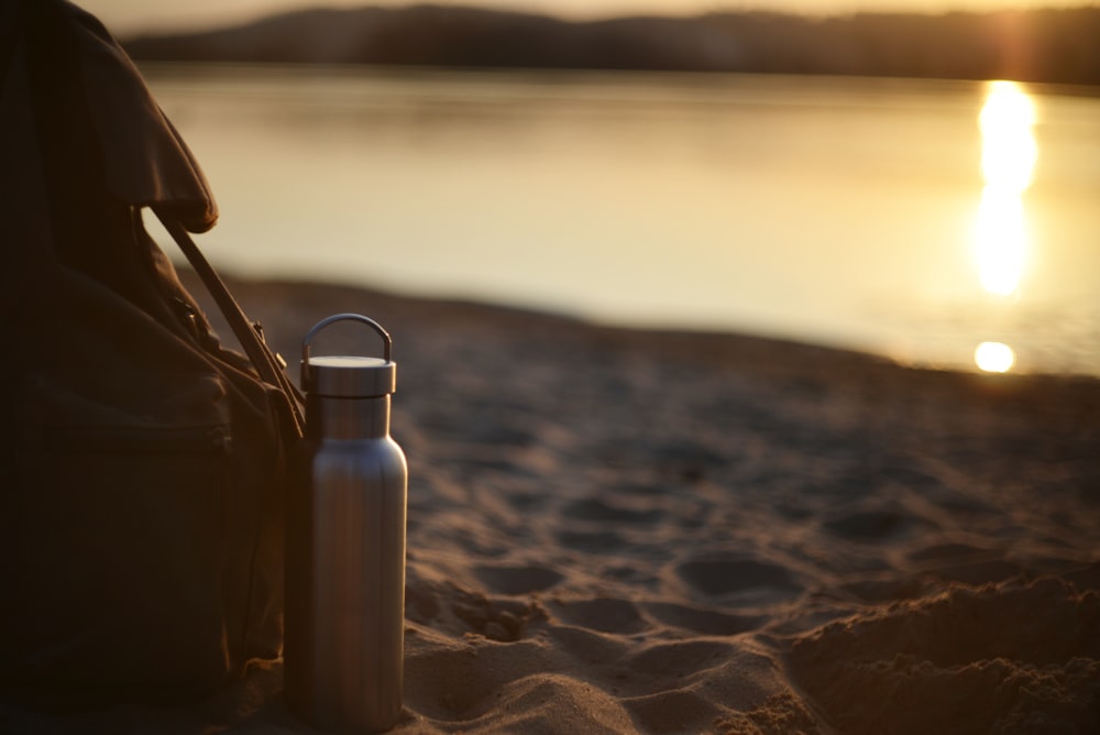 a water bottle sitting on top of a sandy beach