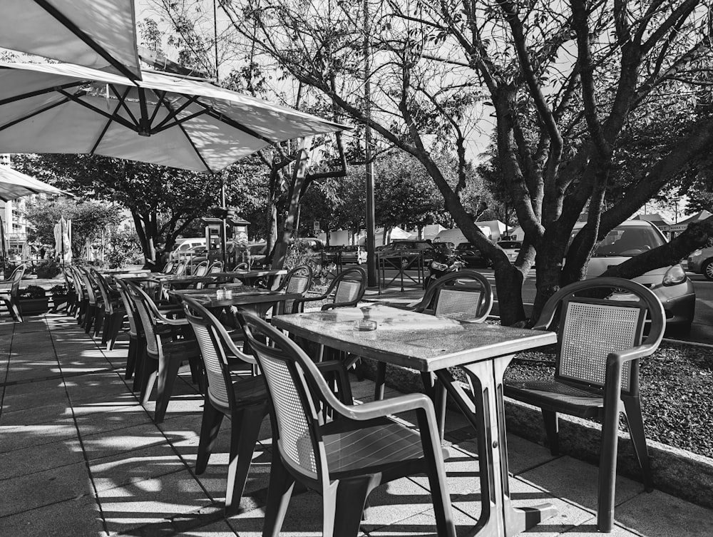a black and white photo of tables and chairs under umbrellas