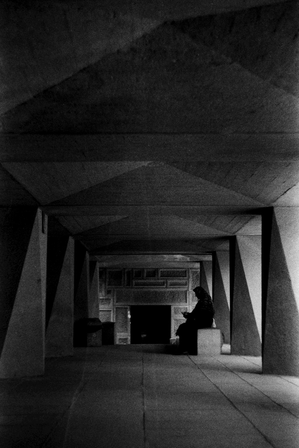 a black and white photo of a person sitting in a tunnel