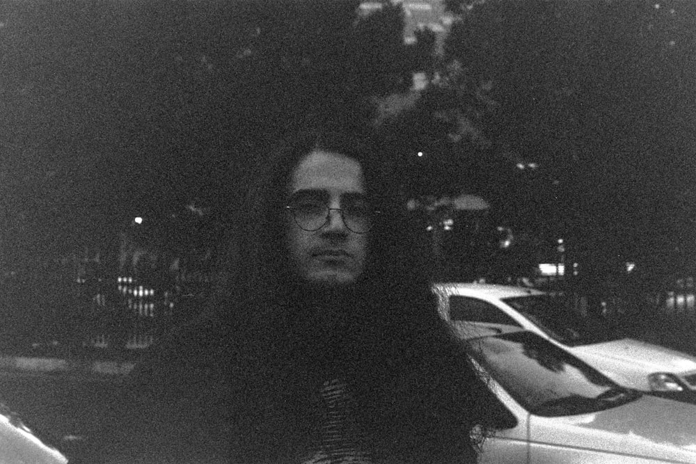 a black and white photo of a man in front of a car