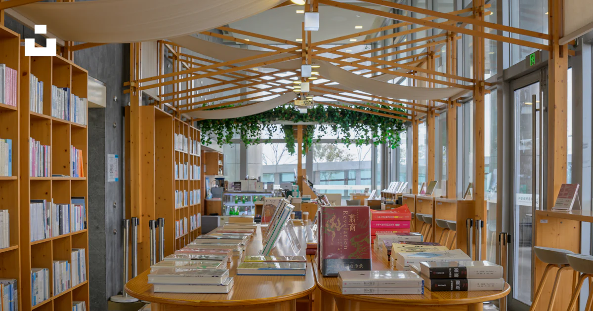 A library filled with lots of books and wooden tables photo – Free ...