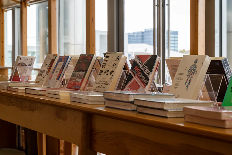 まちの本屋：木のカウンターに本が並び、大きな窓から通りの光が入る書店