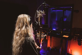 a woman with long hair standing in front of a microphone